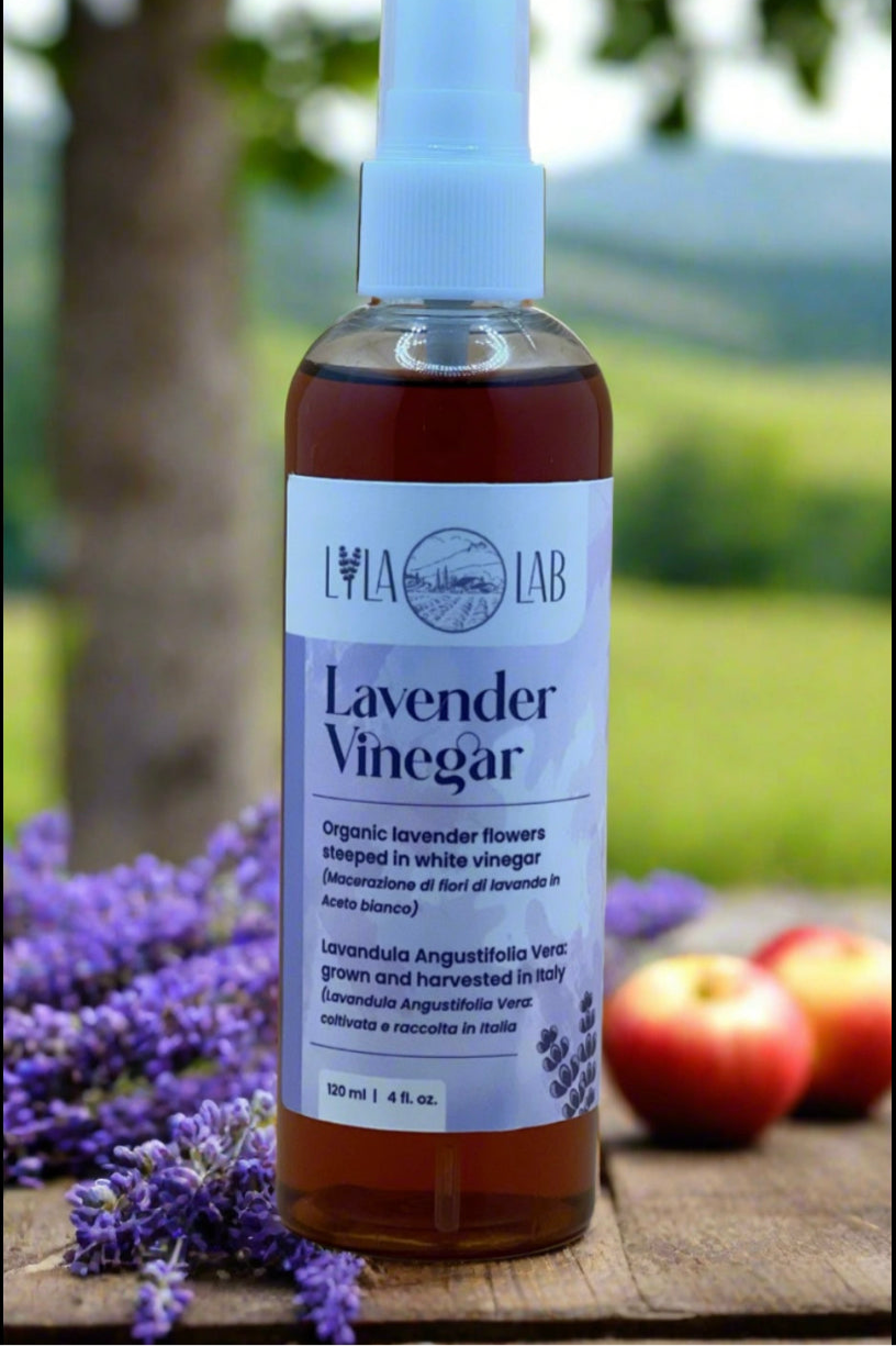 Bottle of Lavender Vinegar with a label on a wooden surface with lavender and apples in the background.
